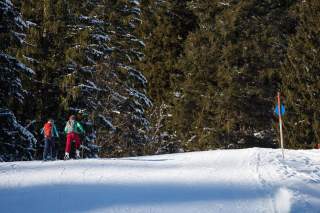 Zwei Menschen gehen mit Ski Piste hoch