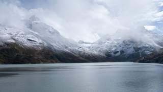 Im Vordergrund ein Stausee, im Hintergrund viele breite, schneebedeckte Gipfel.