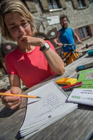 Eine Frau sitzt an einem Tisch auf dem ein Notizblock liegt