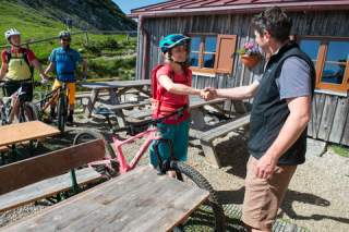 Handschlag zwischen zwei Personen vor einer Hütte