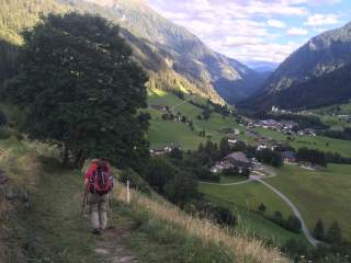 Mensch wandert Bergweg in Dorf hinab