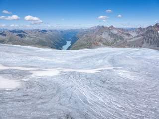 Große Gletscherfläche mit Spalten, schroffe alpine Gipfel im Hintergrund, Tiefblick ins Kaunertal