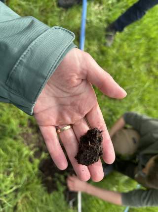 Ein Stück Torf wird in einer ausgestreckten Hand gezeigt.