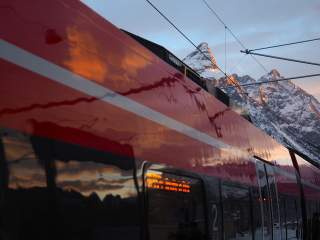 Nahaufnahme eines roten Zugs vor verschneiten Bergen