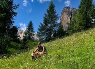 Frau mit Hund in blühender Bergwiese