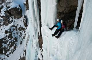 Zwei Frauen beim Eisklettern auf Wasserfall.