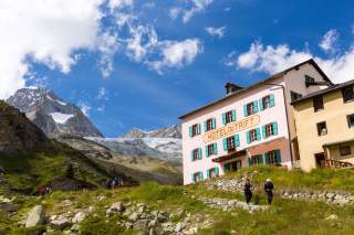 Menschen vor Hütte und Bergkulisse