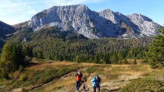Wanderer steigen zur Sella di Val Dolce auf, im Hintergrund ist der Monte Zermula zu sehen.
