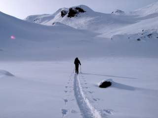 Person geht mit Tourenski durch verschneite Berglandschaft