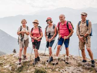 Mehrere ältere Wander*innen posieren für die Kamera auf einem Berggipfel.