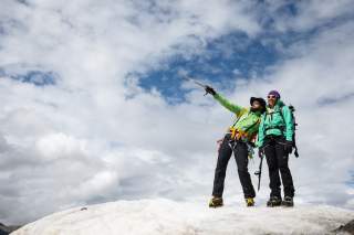 Zwei Menschen stehen mit Steigeisen auf Schnee