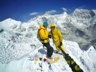 Zwei Männer stehen auf schneebedecktem Gipfel und machen ein Selfie