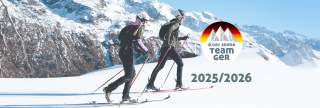 Zwei Skitourengeher mit Helmen und Rucksäcken fahren auf schneebedecktem Gelände vor verschneiten Bergen. Rechts befindet sich das Logo des DAV Skimo Team GER mit der Jahreszahl 2025/2026.