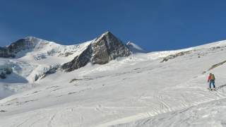 Person steigt mit Tourenski in verschneiter Berglandschaft auf