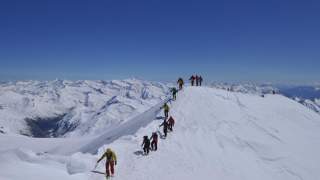 Menschen laufen auf schneebedecktem Gipfelgrat