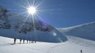 Viele Menschen auf Skitour bei strahlendem Sonnenschein