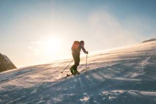 Skitourengeher im Schneesturm bei Sonnenaufgang