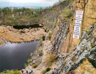 Kletterwand in ehemaligem Steinbruch mit Plakat