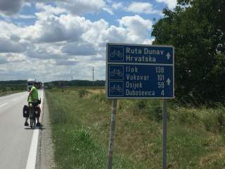 Fahrradfahrer auf Landstraße mit Straßenschild