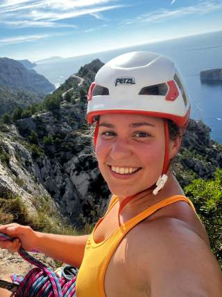 lächelnde Frau mit Helm beim Klettern