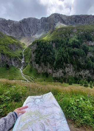 Mensch mit Karte blickt in Berglandschaft