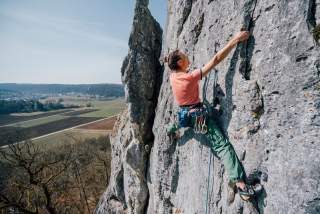 Frau klettert an Felswand in Mittelgebirge