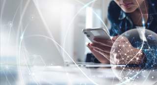 Stockfoto: Eine Frau mit Computer und Smartphone. Stilisiert davor das weltumfassende World-Wide-Web.