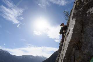 Frau klettert an Felswand