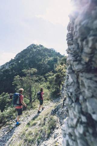 Zwei Menschen wandern auf schmalem Bergweg