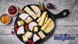 Schwarze Käseplatte mit verschiedenen Käsesorten, garniert mit Feigen, Himbeeren und Schälchen mitMarmelade.